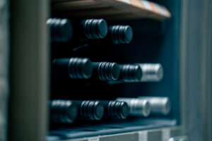 Wine bottles resting on the shelves of a wine cooler