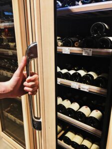 Opening the glass door of a wine cooler